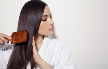 beautiful woman combs her dark long hair with a brush
